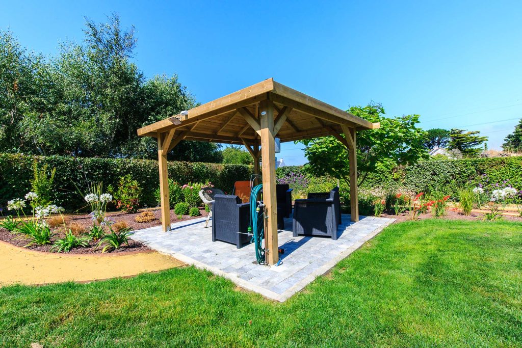 Allée paysagère avec bordures végétales et terrasse sous pergola bois.﻿